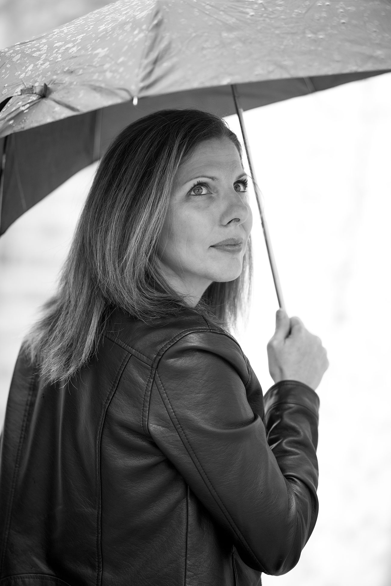 Le Portrait & Mode 34 Femme de 40 ans sous la pluie avec un parapluie, pleine d'émotions dans le regard, photo en noir et blanc.