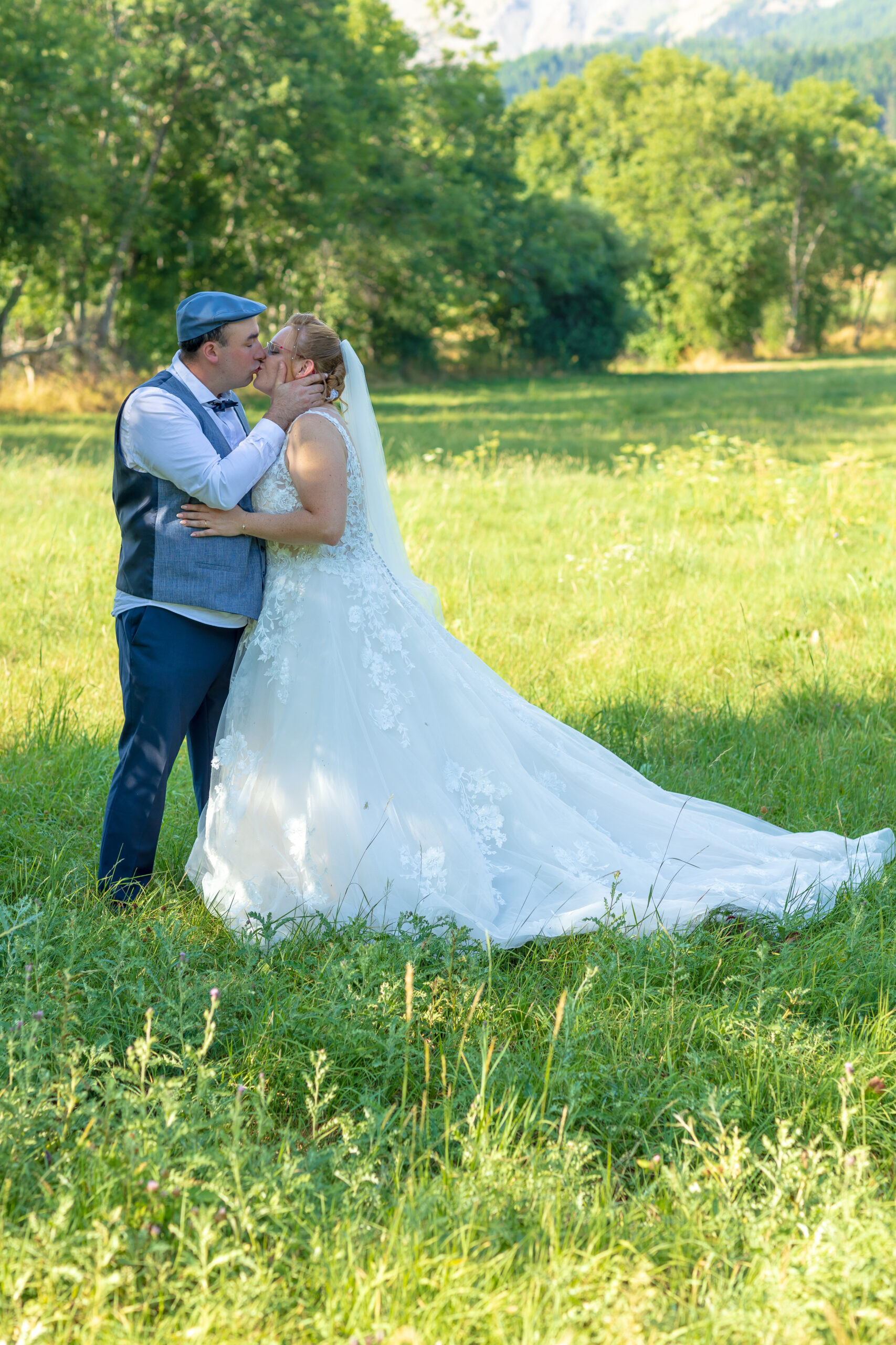 Couple de mariés s’enlaçant dans un parc verdoyant, robe de mariée longue et élégante – M.Studiophoto13