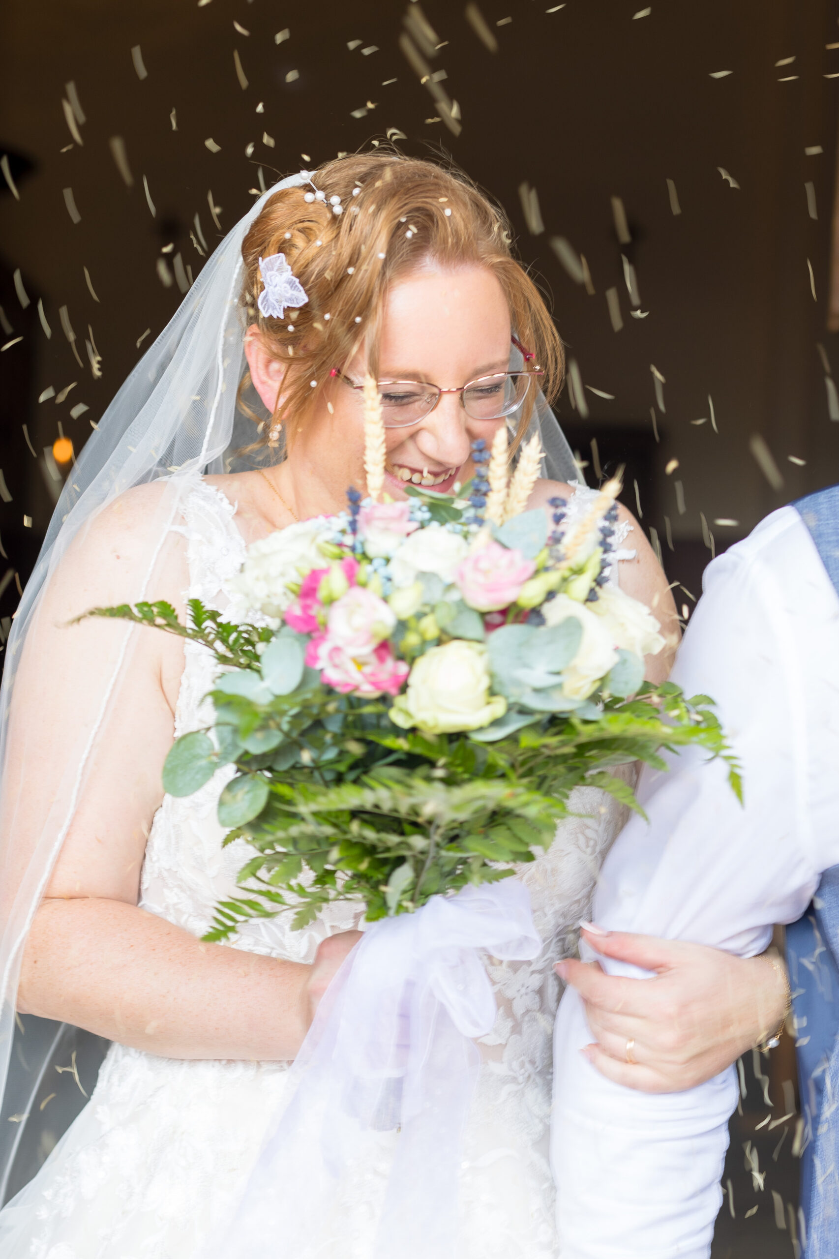 Mariée souriante tenant son bouquet, sous une pluie de confettis à la sortie de la cérémonie – M.Studiophoto13