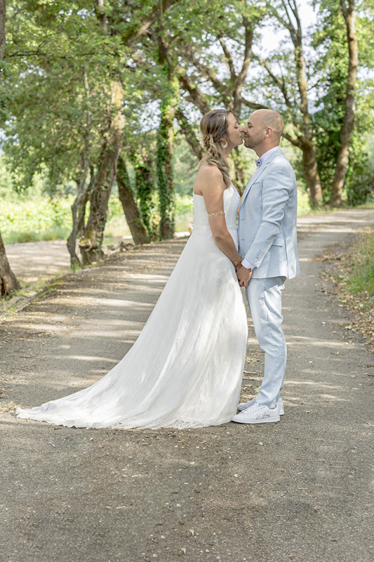 Mariés se tenant par la main dans une allée arborée, moment romantique capturé par M.Studiophoto13