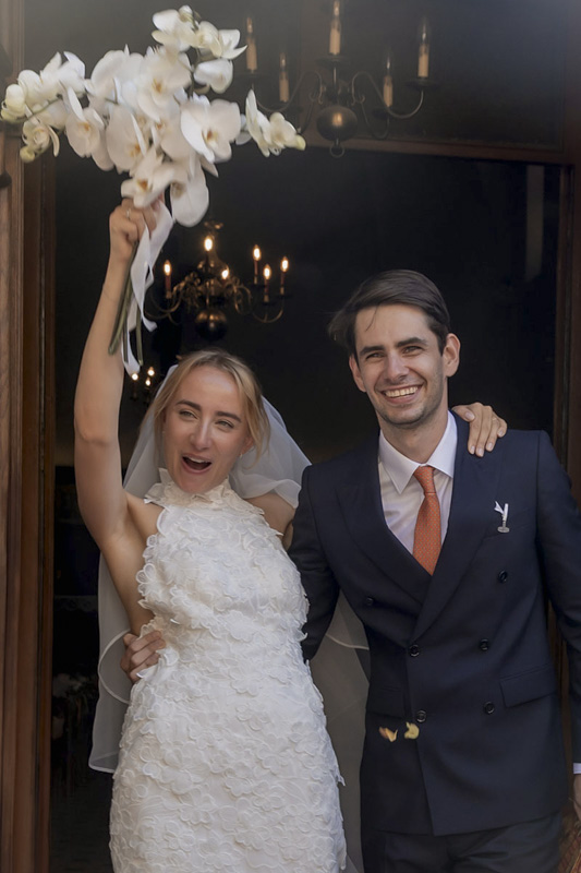 Les mariés rayonnants sortent de la cérémonie, la mariée levant son bouquet en signe de célébration – Photographe de mariage aux Pennes-Mirabeau, Aix-en-Provence et Martigues