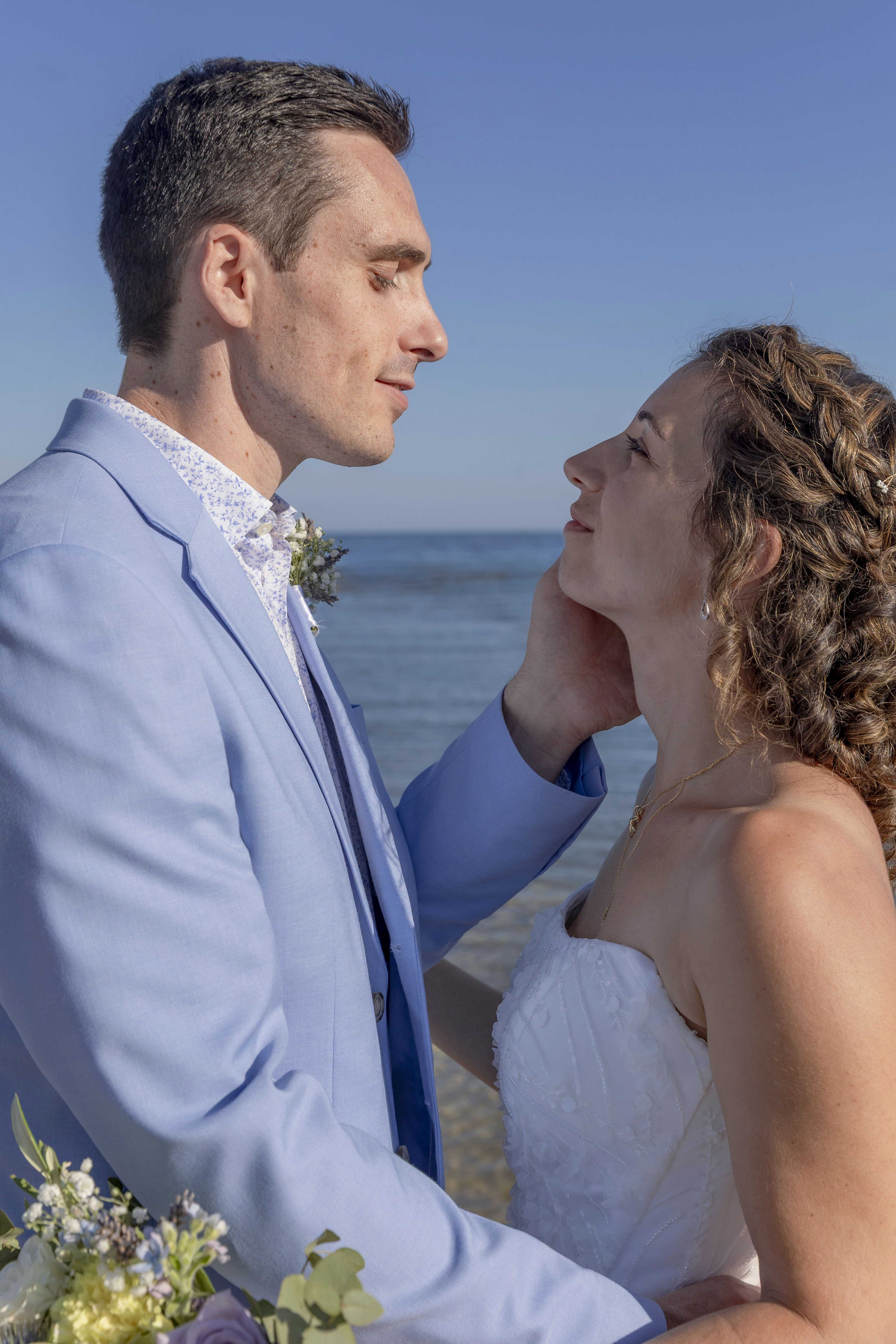 Couple de mariés au bord de la mer, échangeant un regard complice et amoureux – photographie de mariage naturel par M.Studiophoto13